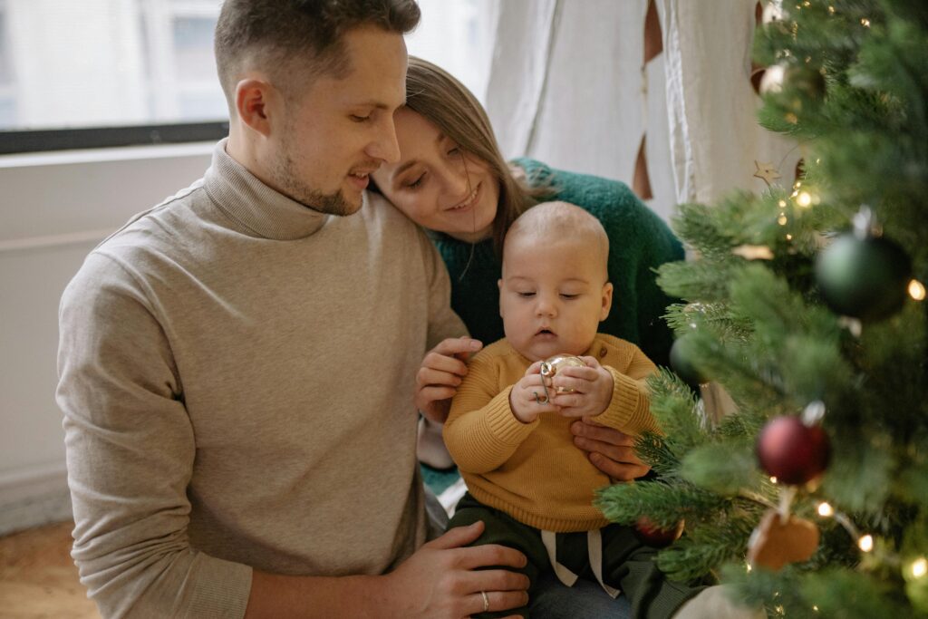 new Parents Holding Their Baby Playing With A Christmas Ball